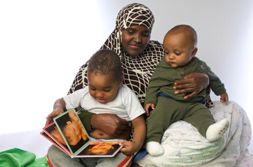baby boys with mother looking at picture book