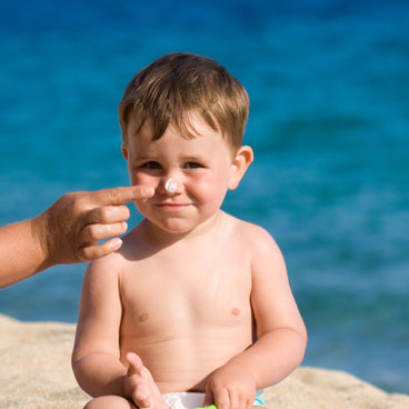 boy at beach with sunscreen on nose