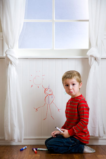preschool boy drawing on wall