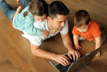 dad using laptop with young boy and girl
